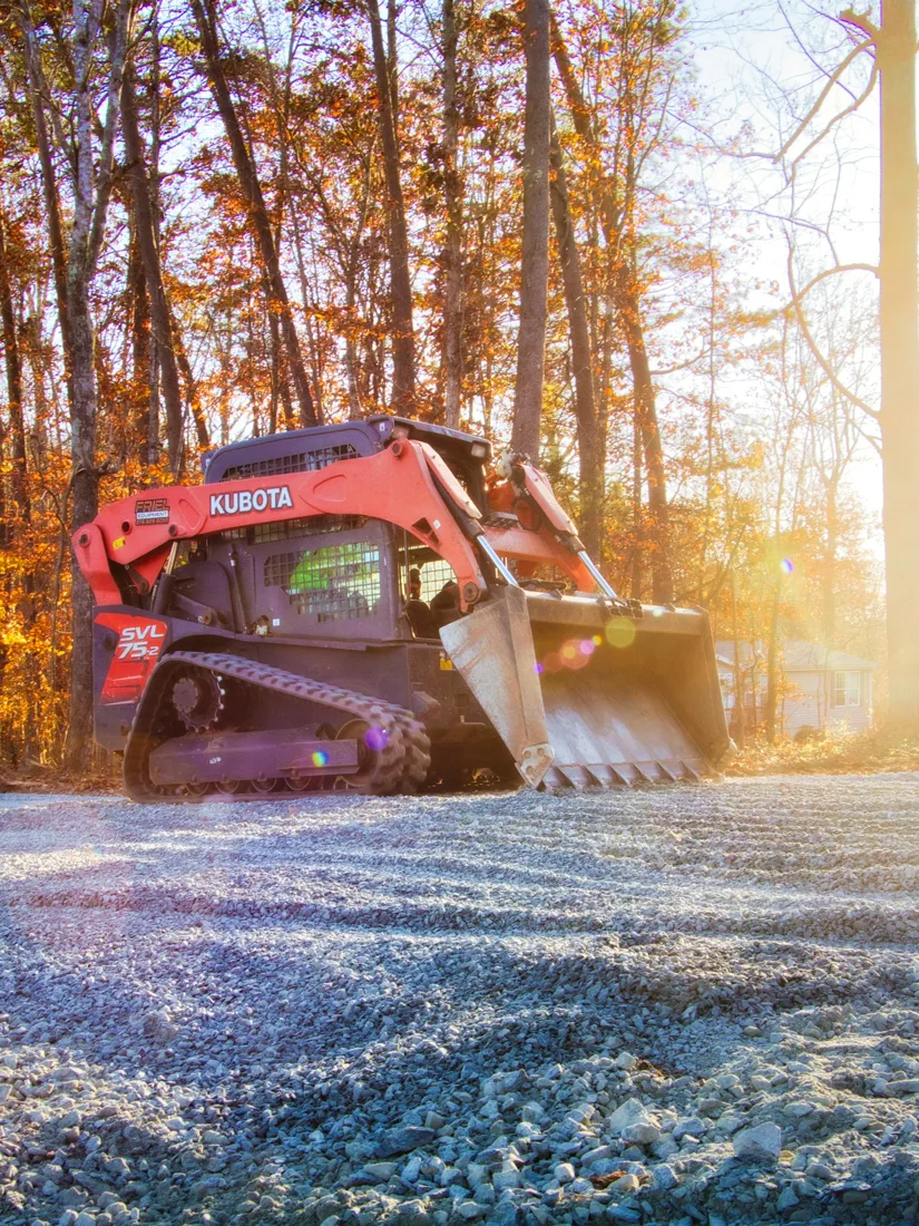 Tracked loader beside a gravel drive