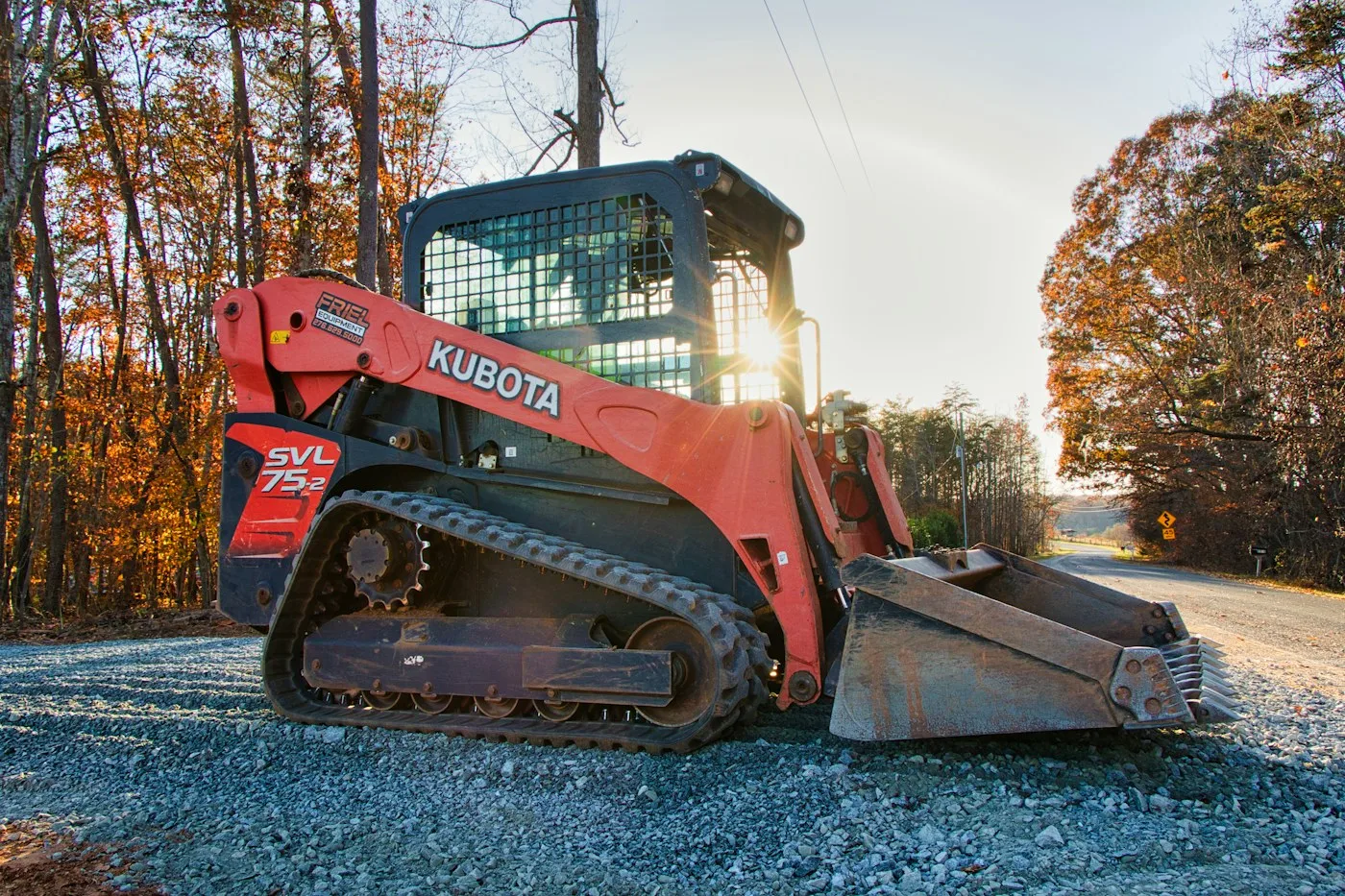 Tracked loader beside trees and gravel